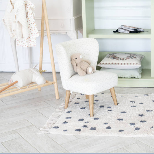 Chambre de bébé élégante avec chaise et ours en peluche, illustrant décoration et confort pour article blog sur chambres d'enfants.